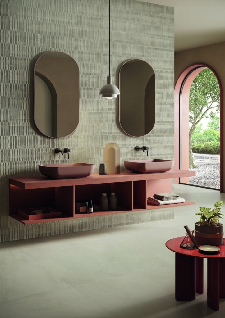 High-end open badkamer met roze tinten en ovale spiegels.